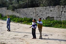 Dinding perbatasan penuh lubang akibat peluru dan pecahan peluru menutupi dinding. Foto diabadikan ketika anak-anak bermain layang-layang di Kota Gaza, 12 Februari 2019. (Foto: Reuters/Arab News)