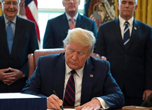 Presiden Amerika Serikat Donald Trump menandatangani Undang-Undang Bantuan Korona, Bantuan, dan Keamanan Ekonomi (CARES), paket penyelamatan $ 2,2 triliun untuk memberikan bantuan ekonomi di tengah wabah koronavirus. (Fotto: AFP/Al Jazeera)