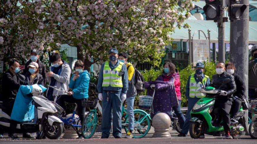 Orang-orang berhenti di persimpangan saat momen berkabung nasional untuk para korban coronavirus di Beijing pada hari Sabtu (4/4). (Foto: AP/Al Jazeera)