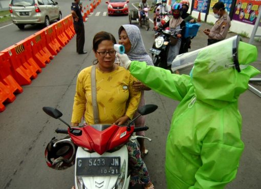 Seorang petugas medis yang mengenakan pakaian pelindung, memeriksa seorang wanita dengan pemindai termal di tengah wabah penyakit corona (COVID-19), di Tegal, Jawa Tengah.(Foto: Reuters/Al Jazeera)