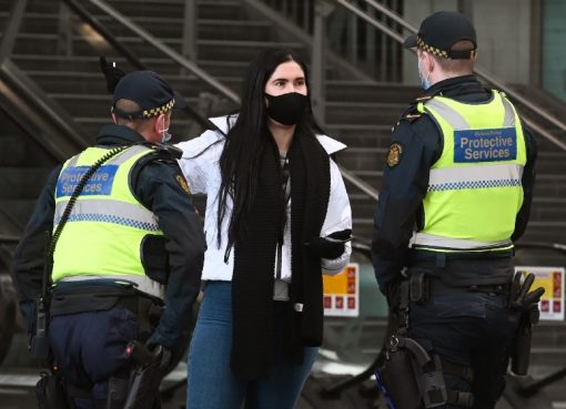 Petugas layanan perlindungan berbicara dengan seorang wanita di Stasiun Southern Cross, di Melbourne pada 7 Agustus 2020, saat kota tersebut dikunci secara ketat. (Foto AFP/ Al Jazeera)